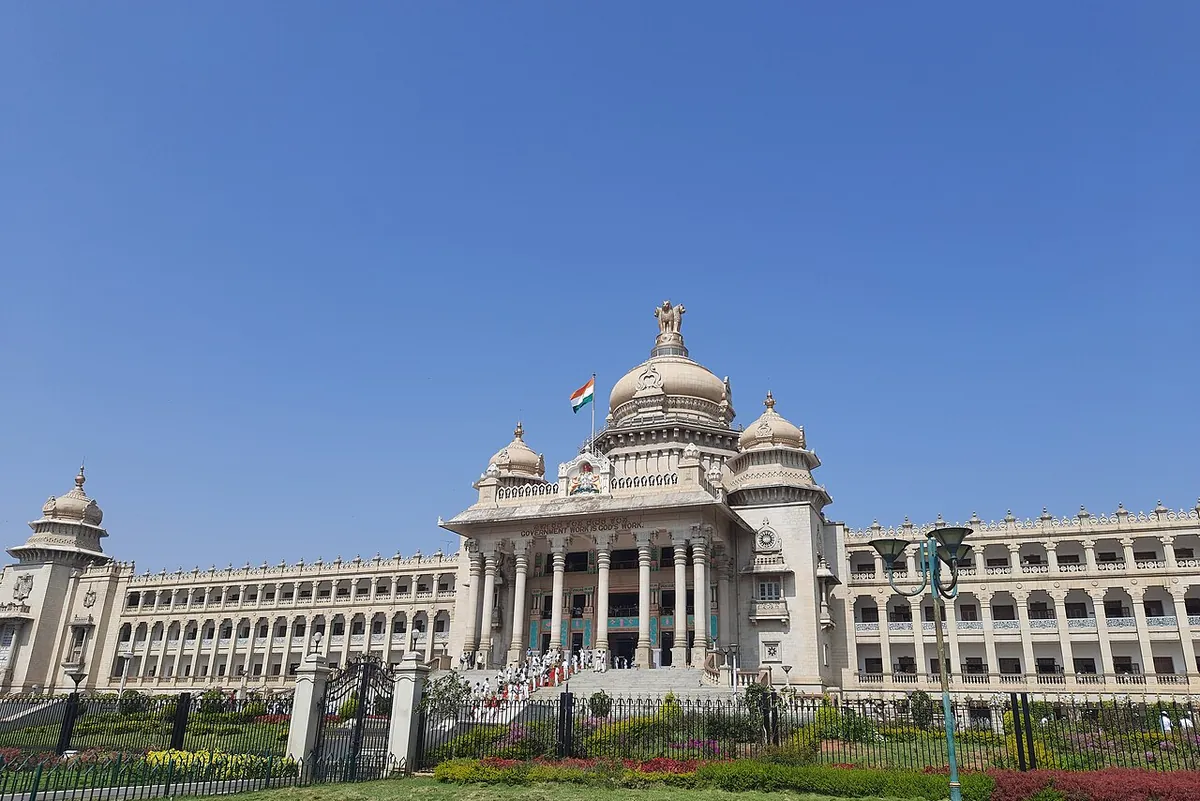 The Vidhana Soudha in Bengaluru under a clear blue sky, its central dome topped by the national emblem