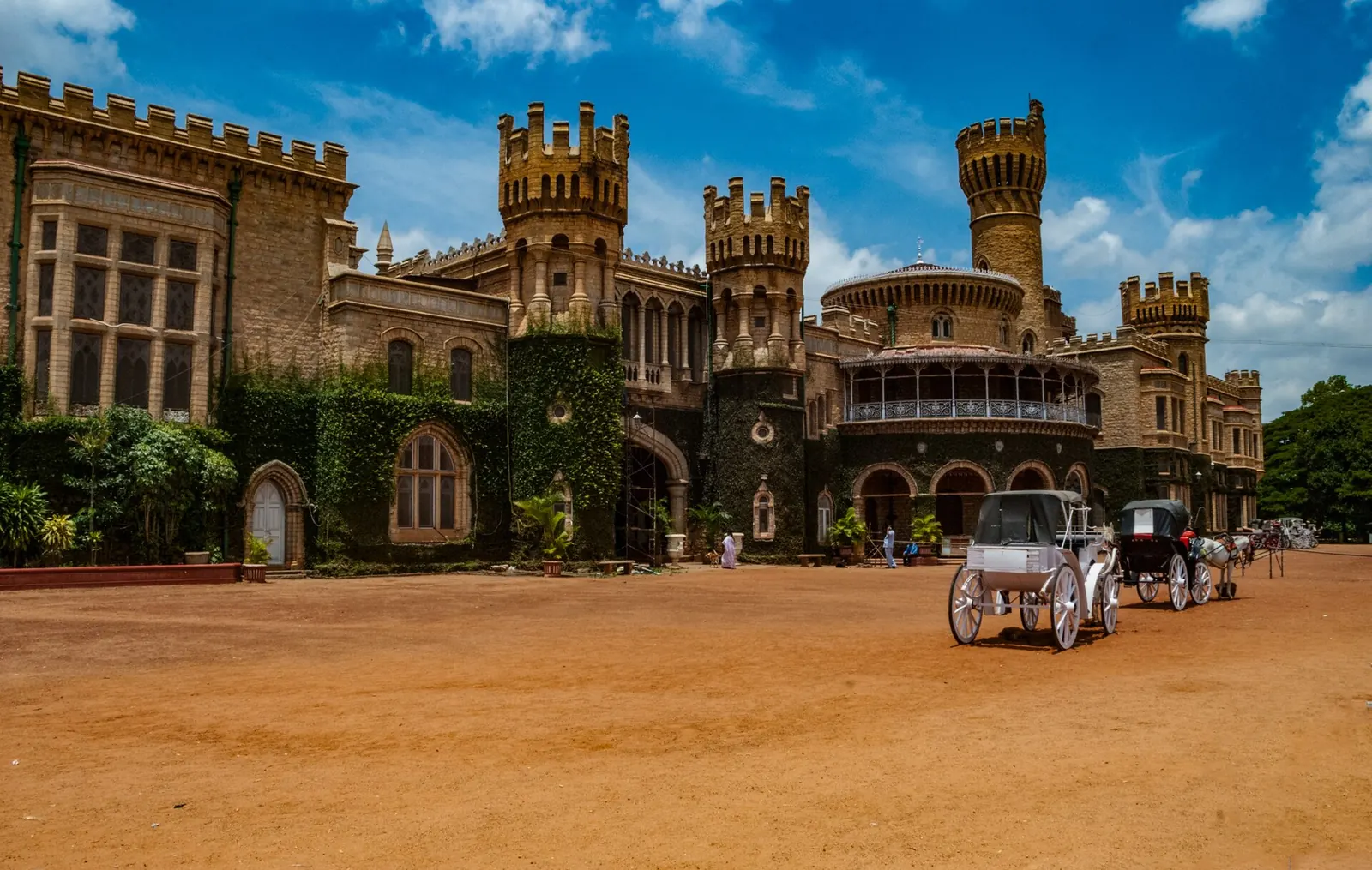 Bangalore Palace in Bengaluru, its ivy-covered stone towers and turrets under a bright blue sky