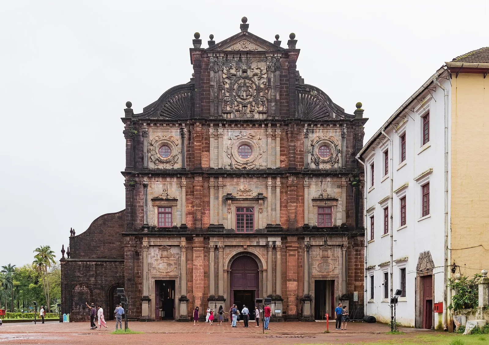 The laterite facade of the Basilica of Bom Jesus in Old Goa, with visitors at its doors