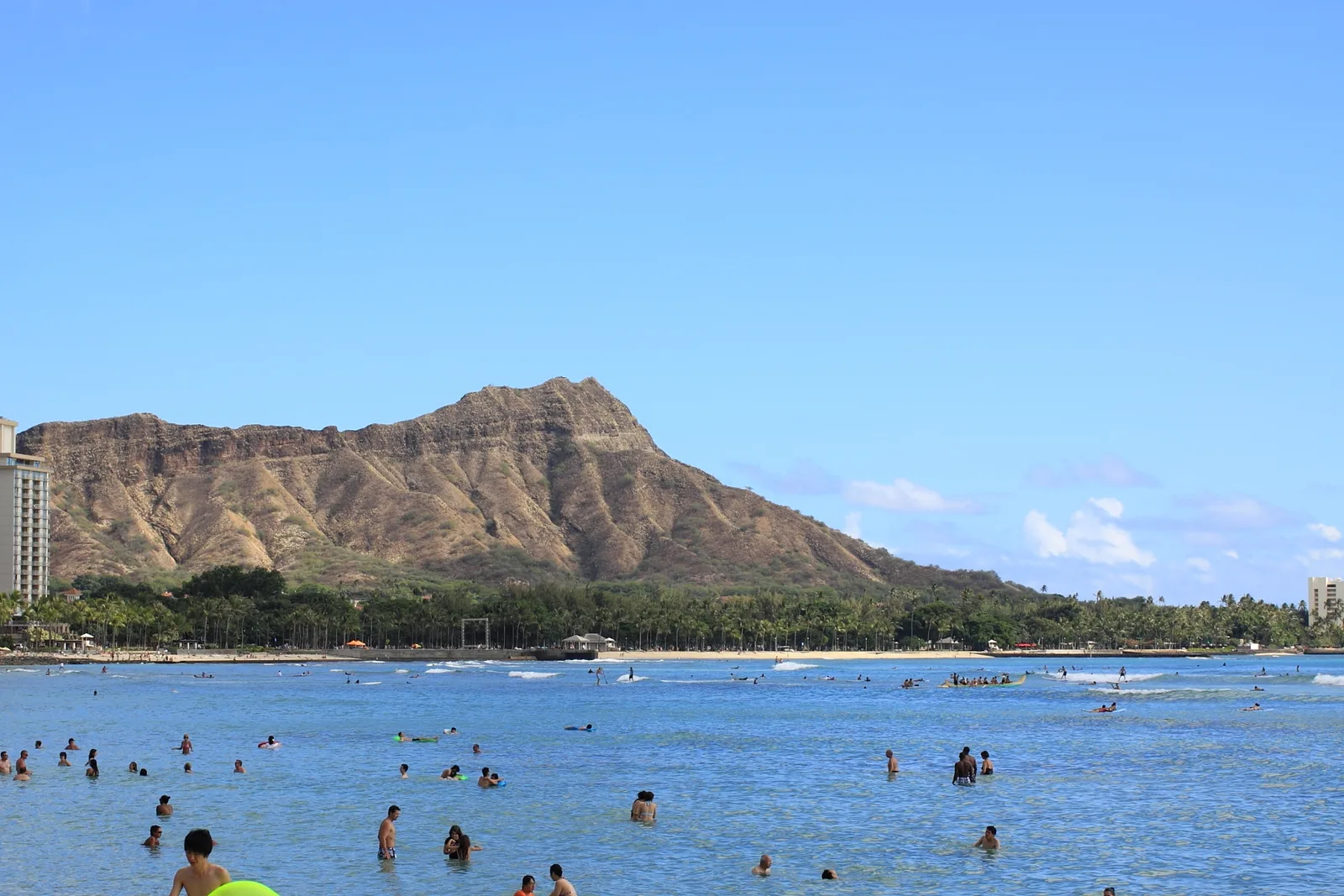 Waikiki Beach with Diamond Head behind it, swimmers and surfers in clear blue water