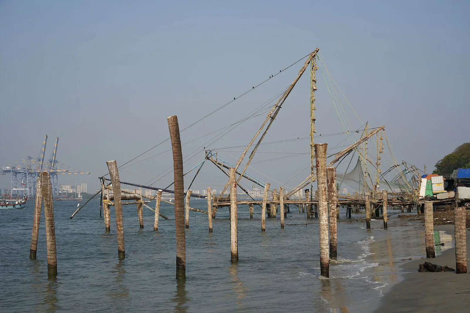 Chinese fishing nets along the Fort Kochi shore, with the harbour cranes behind them