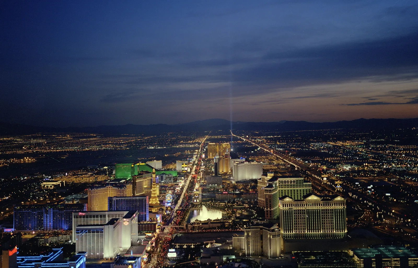 The Las Vegas Strip at dusk seen from above, its lights stretching south through the city
