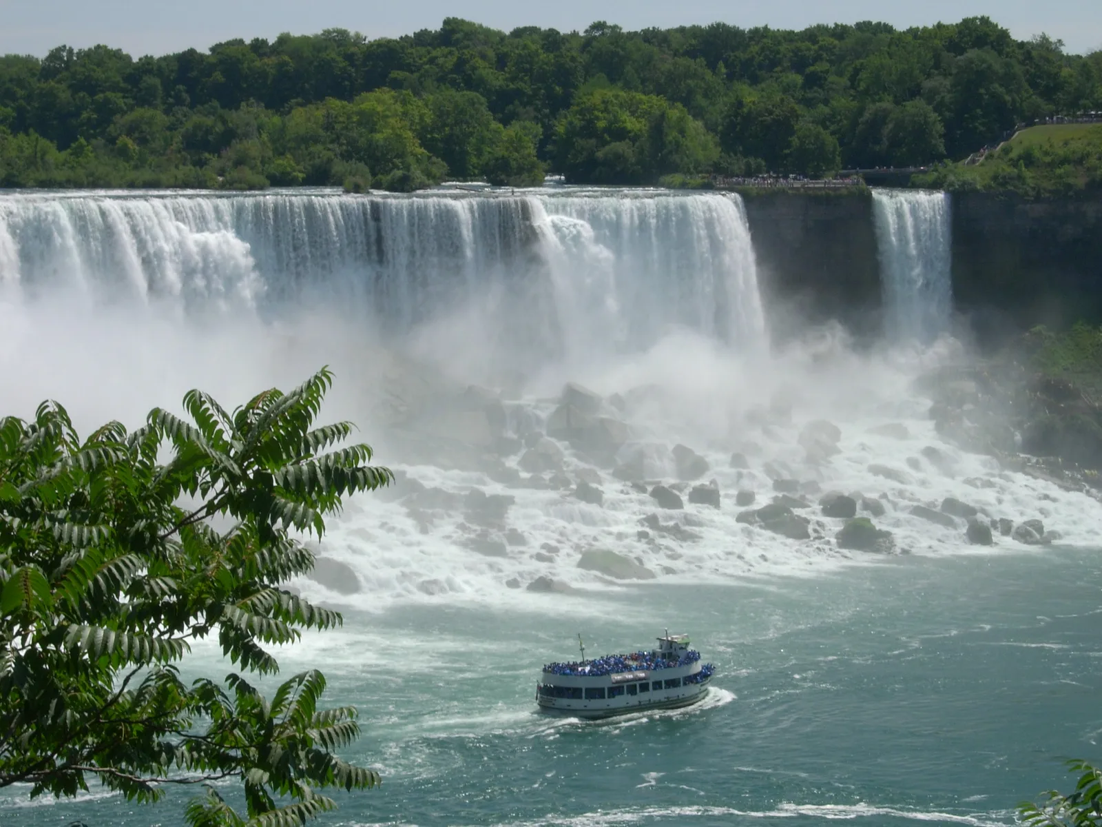 The American Falls and Bridal Veil Falls pouring onto their boulders, with a Maid of the Mist boat crossing the river below