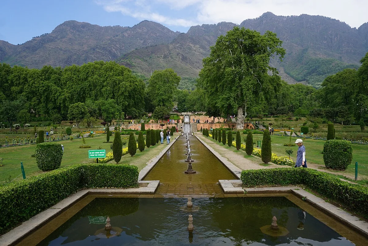 The terraced lawns and central water channel of Nishat Bagh in Srinagar, fountains running down towards Dal Lake with the Zabarwan hills behind
