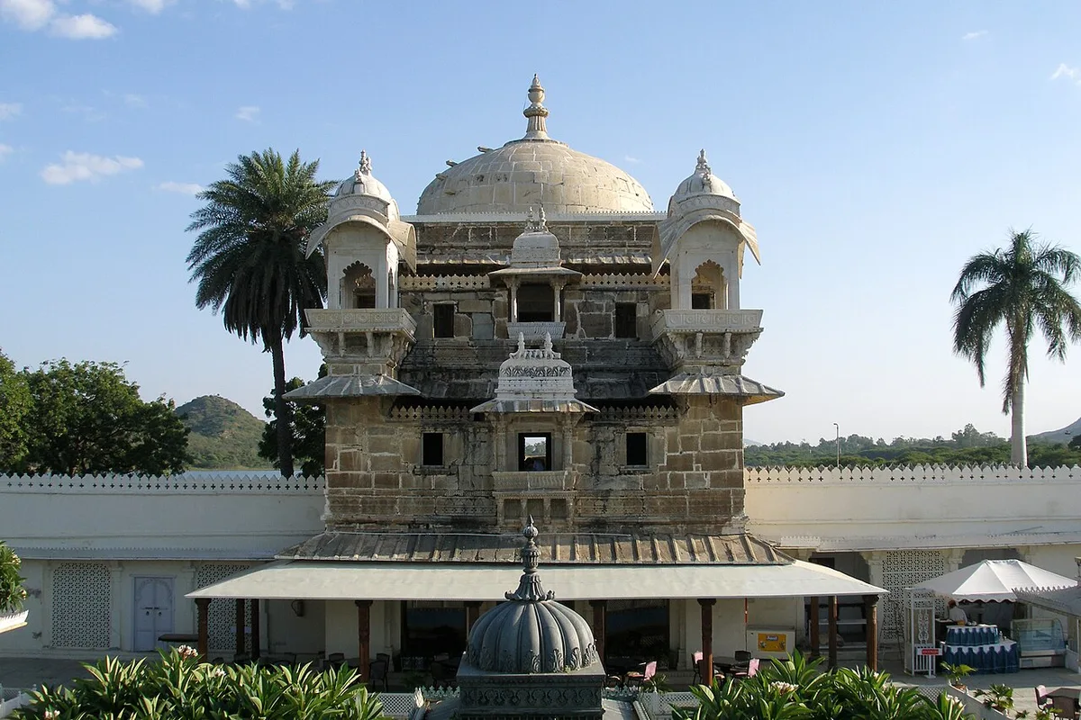 The domed Gol Mahal palace building on Jag Mandir island in Lake Pichola, with carved corner towers and a courtyard in the foreground
