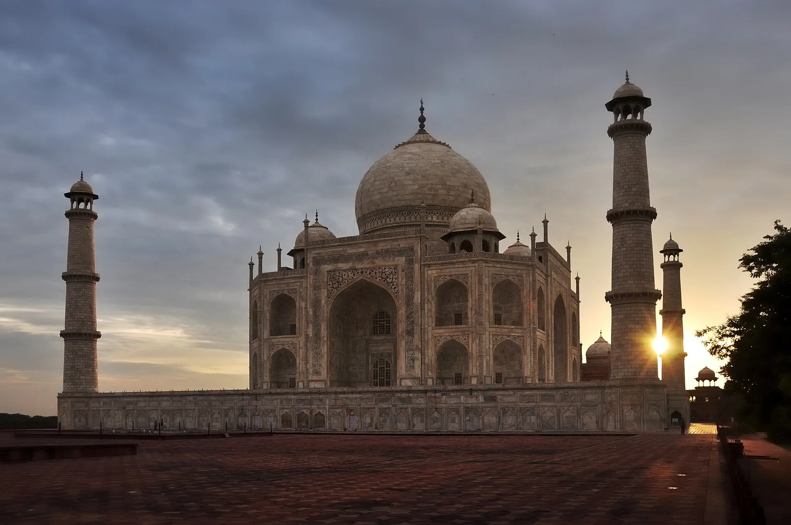 The Taj Mahal at sunrise, its white marble dome and minarets against a dawn sky