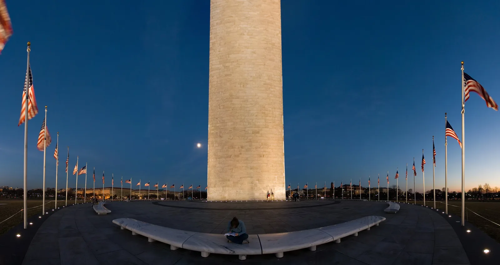 The base of the Washington Monument at dusk, ringed by its circle of American flags